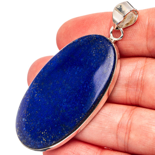 Oval lapis lazuli pendant with sterling silver bail, blue stone held in hand