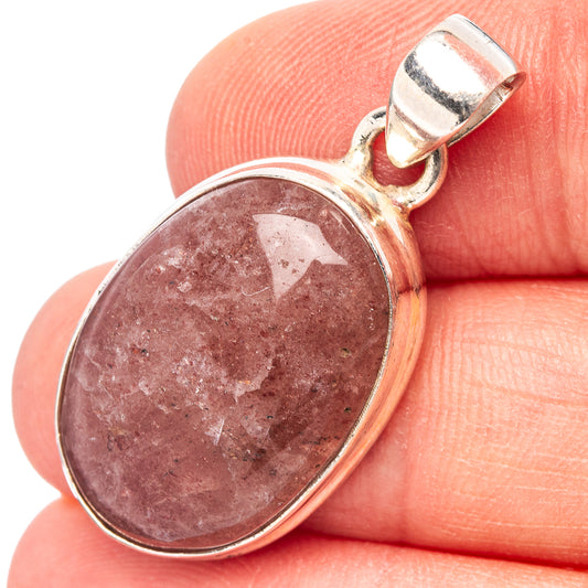 Oval strawberry quartz pendant in .925 sterling silver bezel with bail, close-up on hand