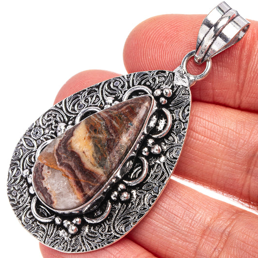 Antique silver-tone teardrop opal pendant close-up with ornate border and loop bail