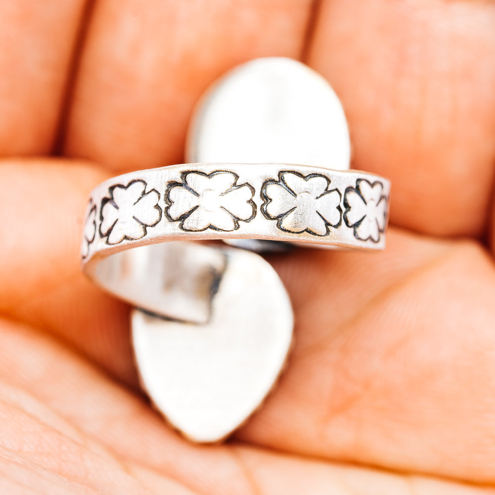 Sterling silver band ring with repeating floral cutout pattern; stones not visible