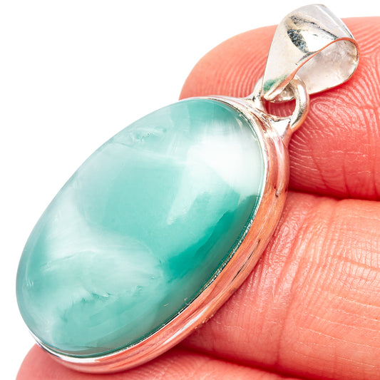 Teal oval stone pendant with .925 sterling silver bail, close-up on finger