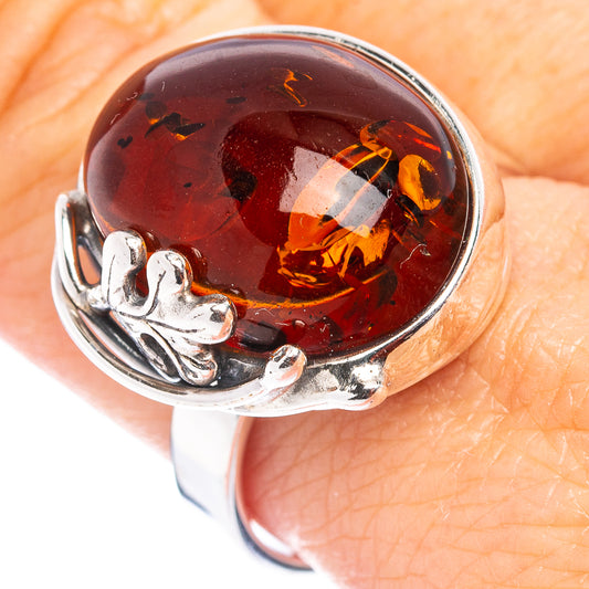 Adjustable sterling silver ring with round red Baltic amber cabochon on finger