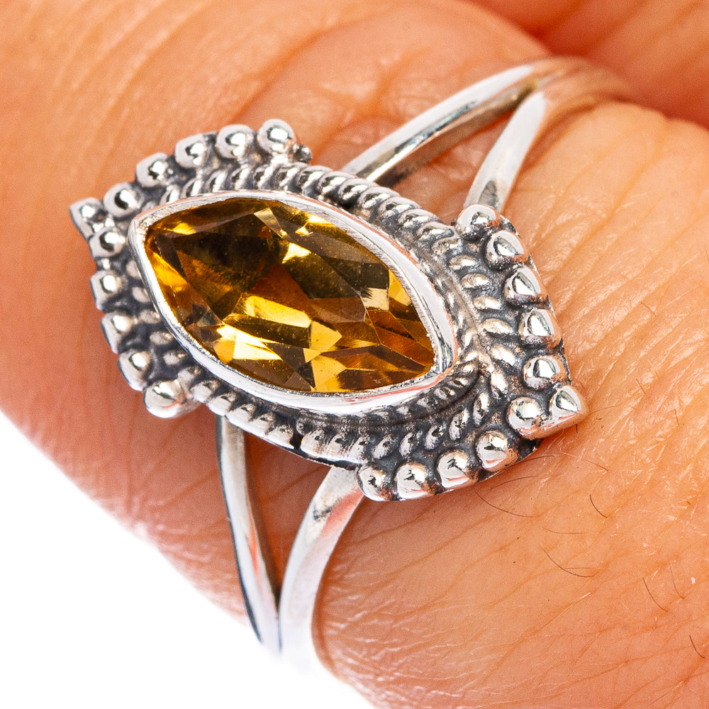 Faceted oval citrine ring in 925 silver, detailed textured border, close-up on finger