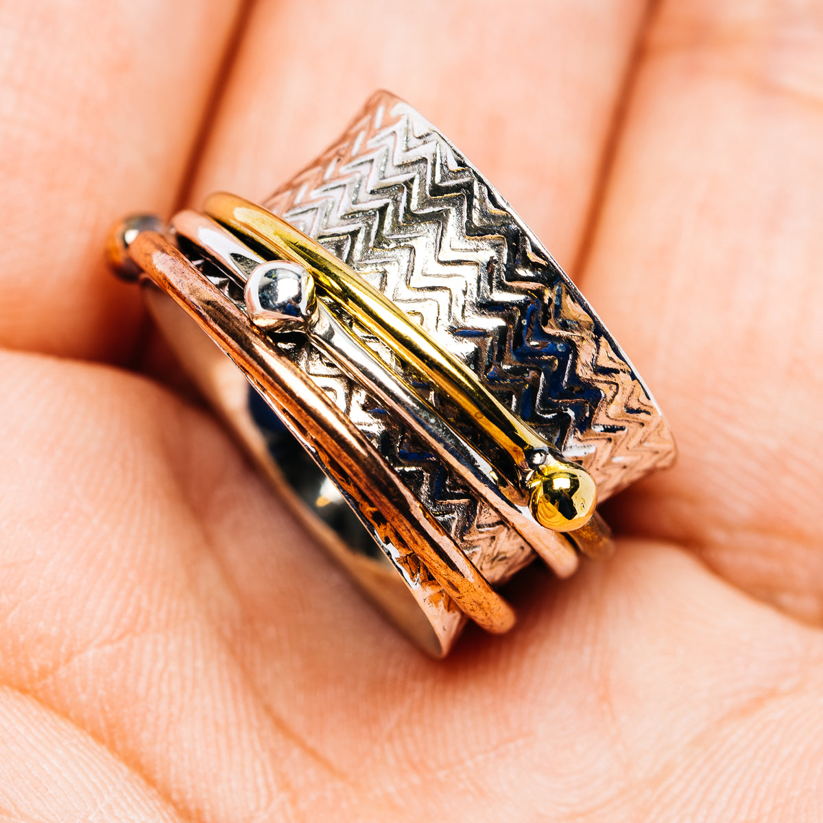 Spinner ring with zigzag etching, round gemstone set, and mixed metal gold accents