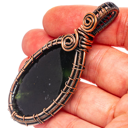 Wire-wrapped teardrop pendant with dark oxidized copper frame and black gemstone slice