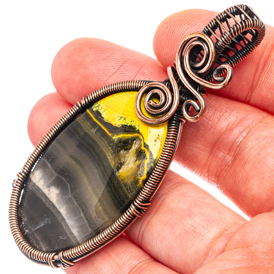 Oxidized copper wire-wrap pendant with oval yellow and gray jasper stone and coiled bail loops