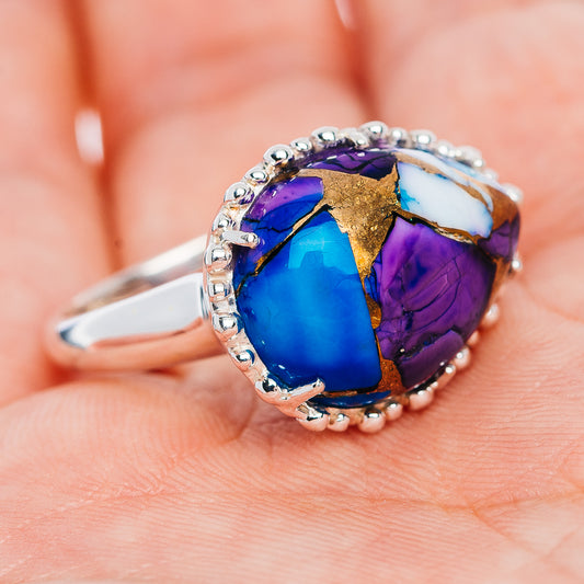 Oval blue and purple gemstone ring with gold matrix accents and silver bead border