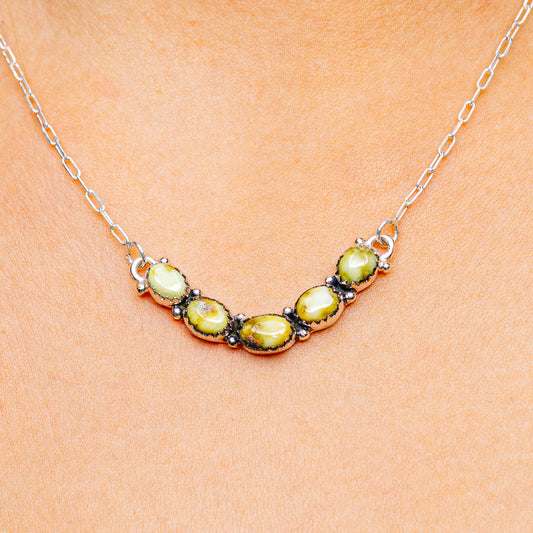 Sterling silver necklace with oval green gemstones in a curved row and chain link.