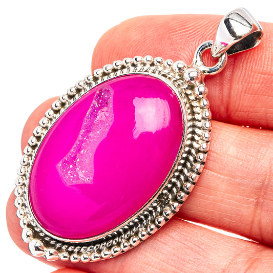 Pink agate druzy oval pendant in .925 sterling silver with silver bail, on finger