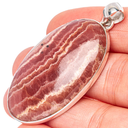 Oval rhodochrosite pendant with maroon and cream striated stone, sterling silver bezel.