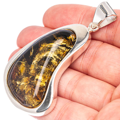 Teardrop amber pendant set in polished 925 sterling silver, held in hand