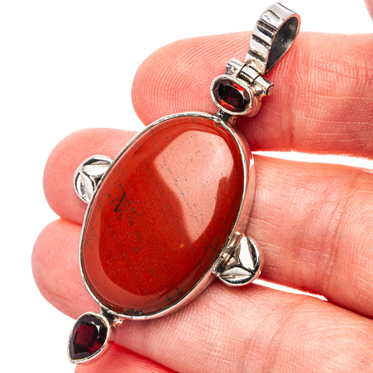 Red jasper oval pendant with sterling silver bail and bezel-set garnet stones