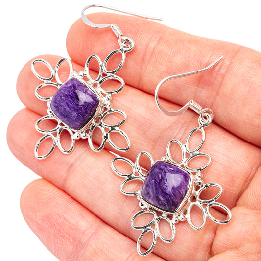 Sterling silver drop earrings featuring purple charoite cabochon with ornate flower-like loops