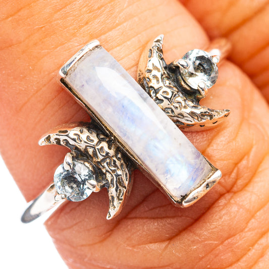Sterling silver ring with rectangular moonstone center, round blue stones, and ornate side scrollwork