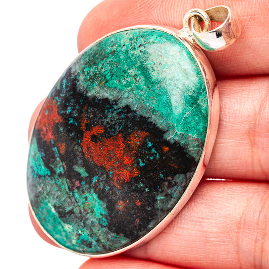 Oval .925 sterling silver pendant with turquoise, black, and orange stone; top loop bail