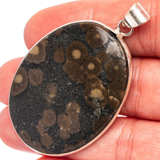Silver-plated round pendant with dark mottled stone and tan spots