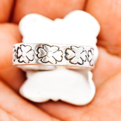 Adjustable silver ring band with four-petal floral cutouts