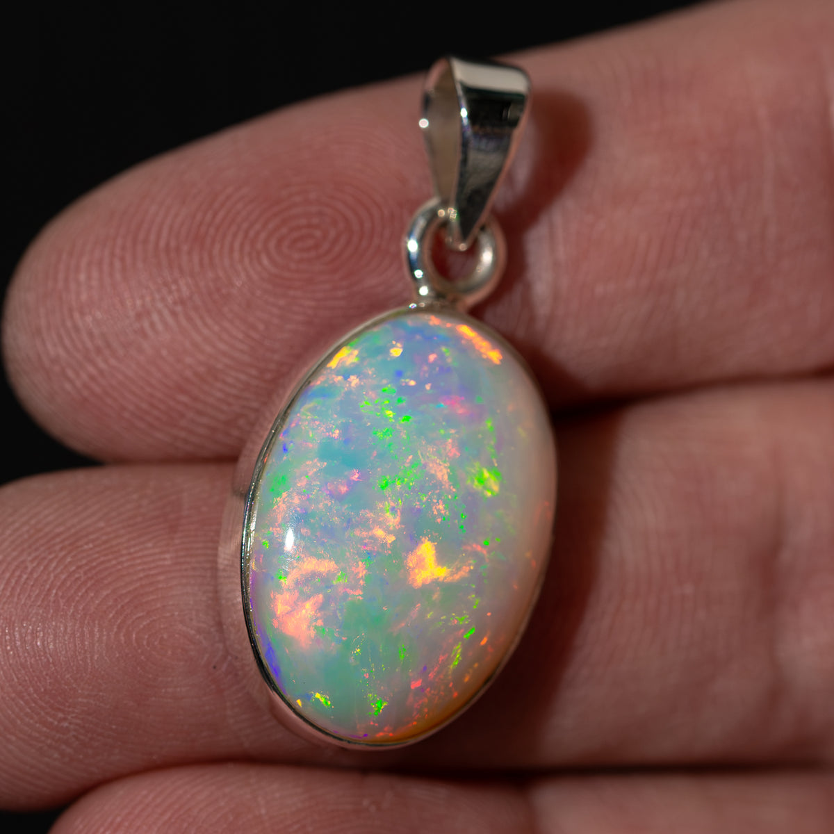 Polished oval opal pendant with .925 sterling silver top bail and multicolor play