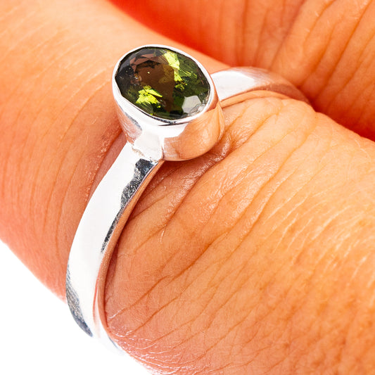Sterling silver ring with oval faceted green moldavite gemstone, reflective bezel setting