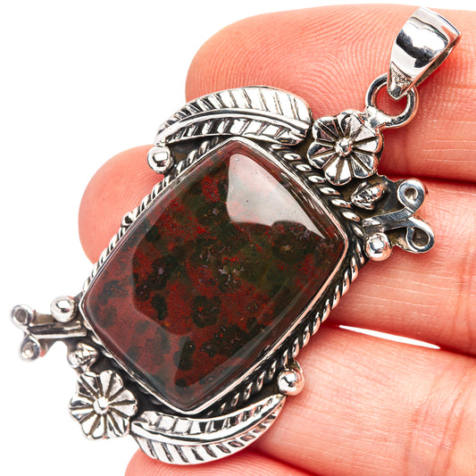 Sterling silver pendant with red-green speckled gemstone and floral accents