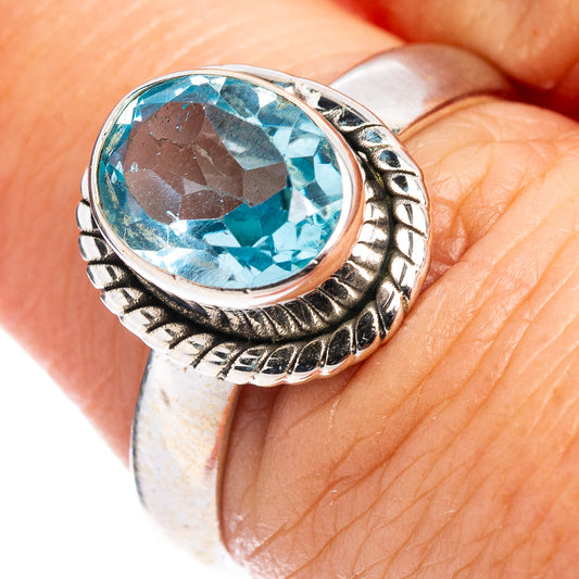 Sterling silver ring with faceted blue topaz center stone, ornate oval bezel