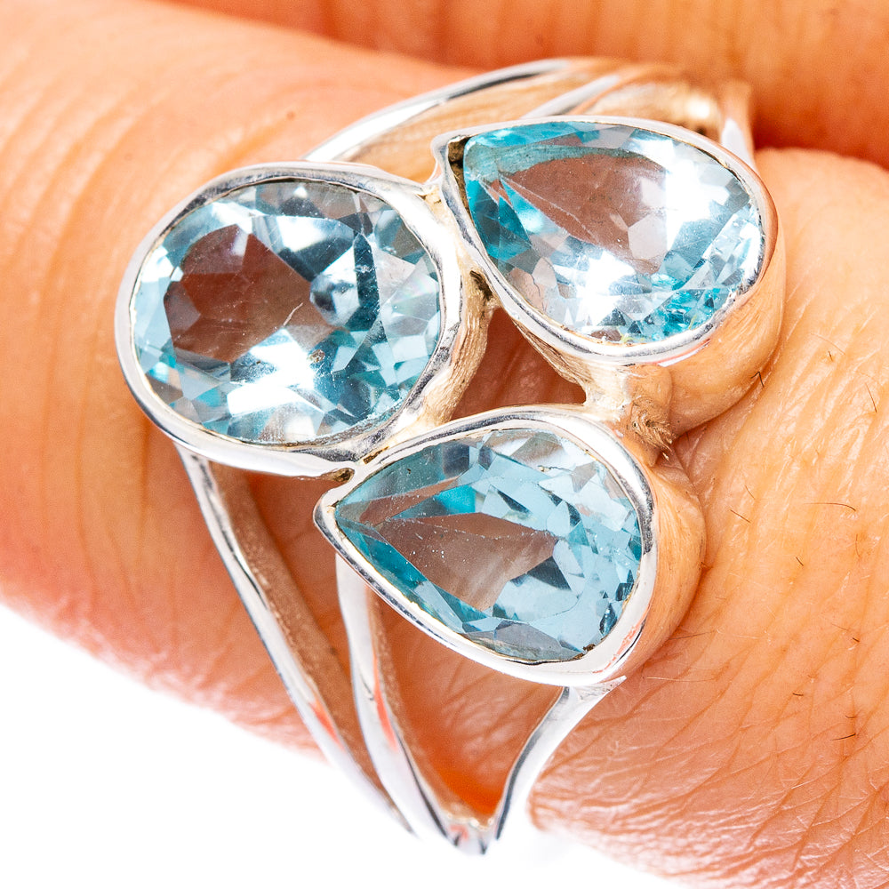 Sterling silver ring on finger with three blue topaz heart stones in shield-like bezel