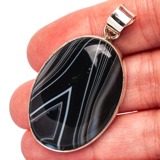 Oval black agate pendant in .925 sterling silver bezel with bail, on fingertip