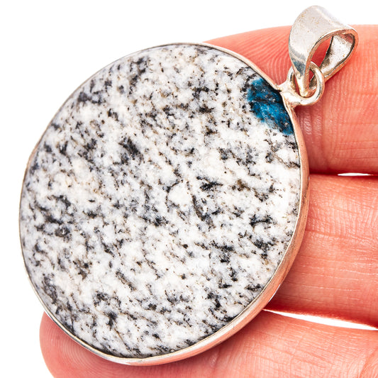 Round silver-plated pendant with white stone speckled with black and a blue streak