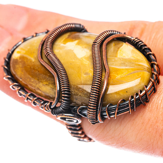 Wire wrap ring with amber petrified palm root slabs and oxidized copper coils on finger