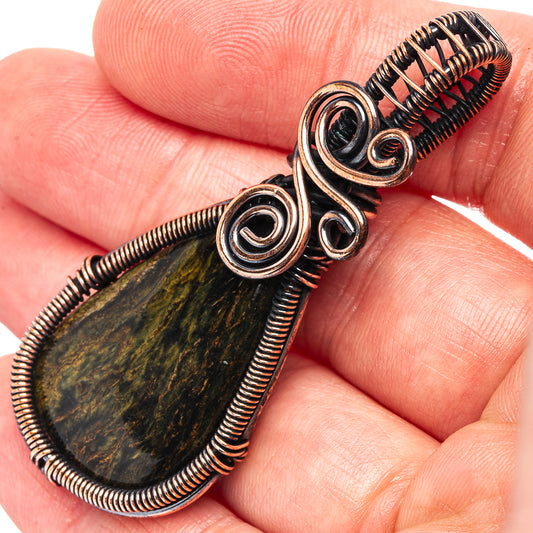 Close-up teardrop wire-wrap pendant with green-gold pietersite and oxidized copper spiral rings