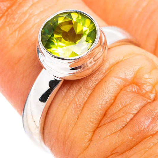 Faceted peridot ring in .925 sterling silver, round green gemstone on finger