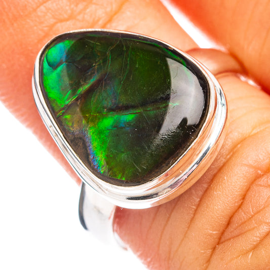 Sterling silver ammolite ring closeup with bright green oval iridescent stone on finger