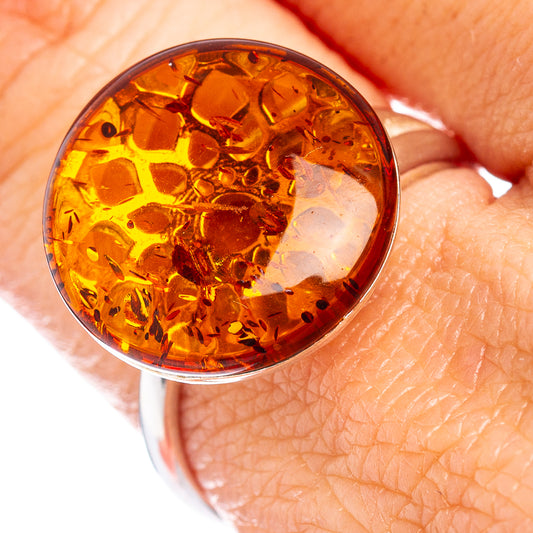 Round amber cabochon on .925 sterling silver ring, shown close-up on finger