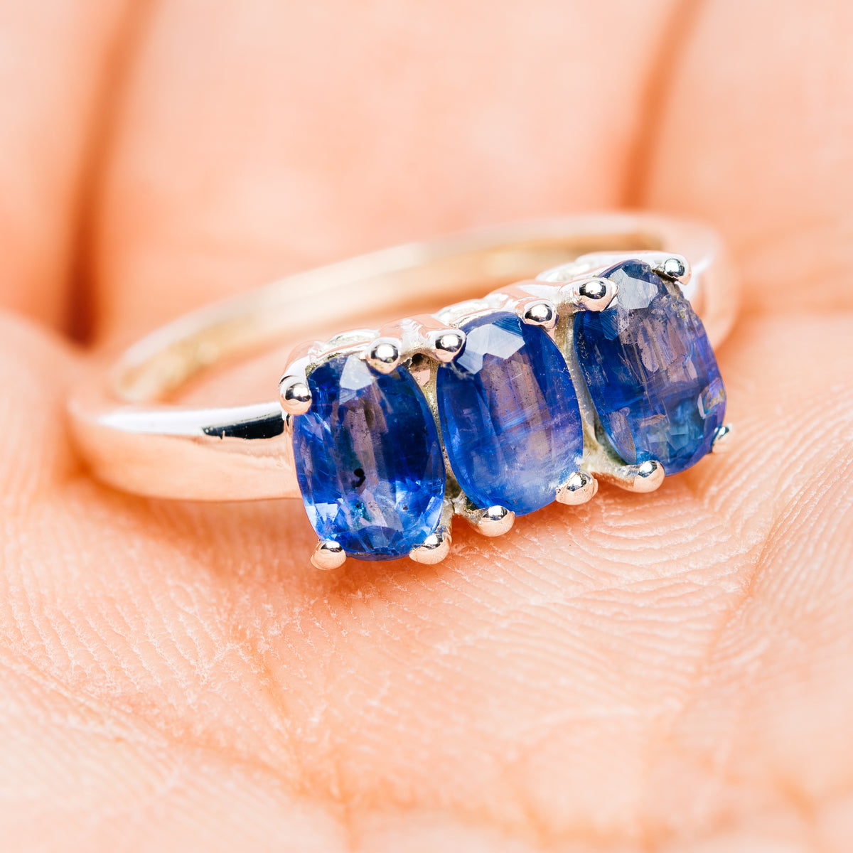 Three-stone blue kyanite ring on finger, oval stones in .925 sterling silver