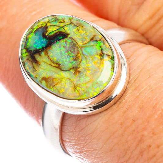 Sterling silver opal ring on hand, close-up of round green-gold iridescent stone