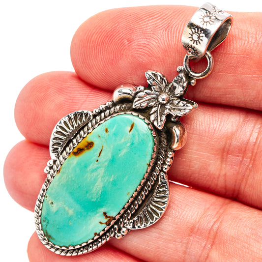 Oval turquoise pendant with ornate .925 sterling silver frame and floral bail