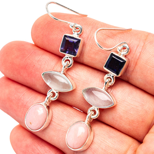Close-up sterling silver earrings with blue square stone, oval moonstone, and pink drops