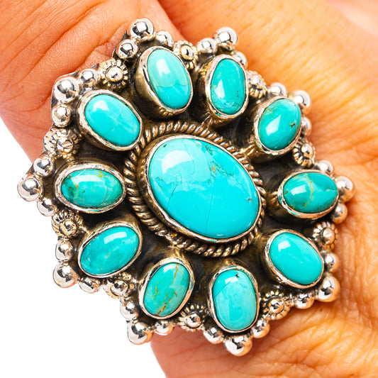 Turquoise cabochon ring with ornate silver setting and large oval center stone.
