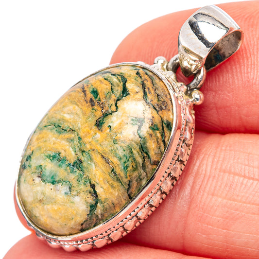Oval mariposite pendant with sterling silver bail and textured oval frame on fingertip
