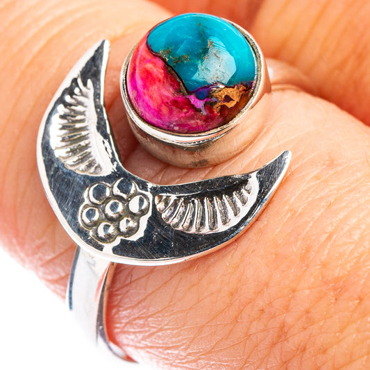 Sterling silver ring with crescent cutouts and oval turquoise-and-pink cabochon on finger
