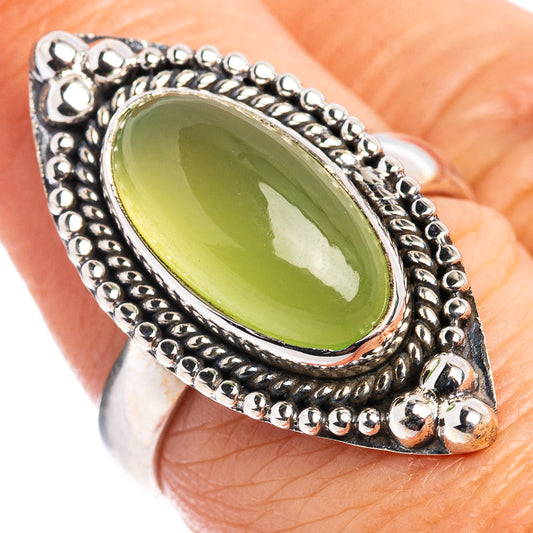 Green oval cabochon silver ring on hand, rope-and-bead border with polished edge