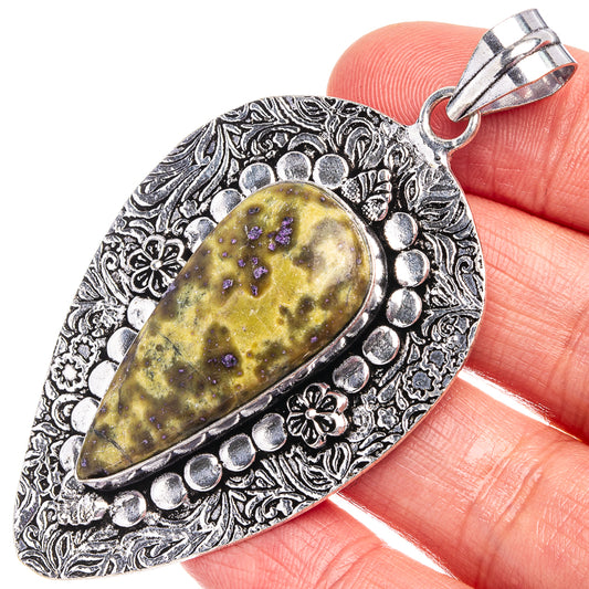 German silver pendant with ornate filigree and teardrop yellow stone with purple specks.