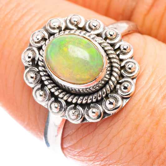 Sterling silver opal ring on finger, round opal cabochon with green and orange glow