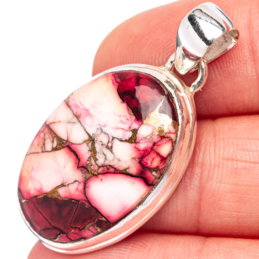 Small oval gemstone pendant close-up, red-pink veining in silver bezel with bail