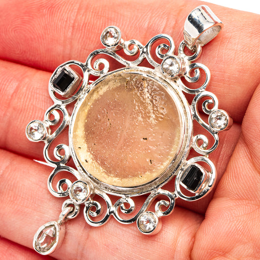 Round cabochon pendant with dark stone bezels and clear halo, silver filigree details