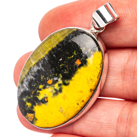 Oval bumblebee jasper pendant with .925 sterling silver bail, worn close-up on hand