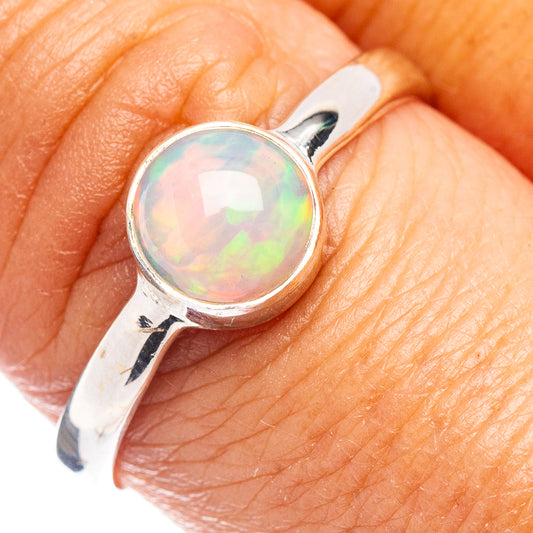 Sterling silver opal ring on finger, round iridescent cabochon and prong mount