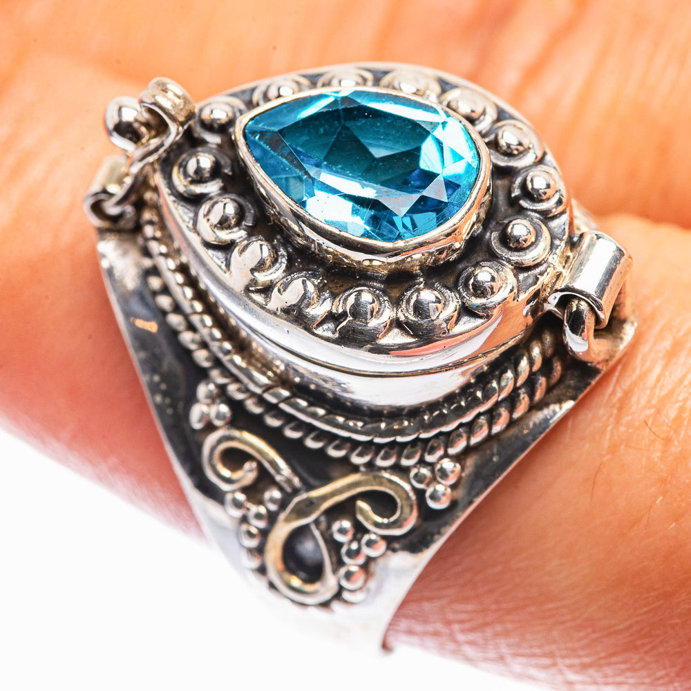 Ornate sterling silver oval blue topaz ring on finger, detailed scrollwork setting