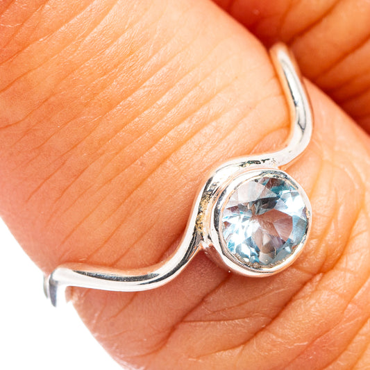Sterling silver open ring with oval blue topaz gemstone, shown on finger