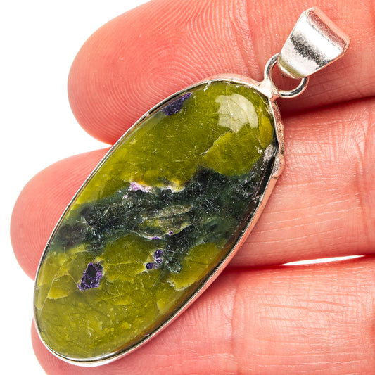 Green oval stichtite pendant on silver-plated loop, purple speckles, shown on fingertip